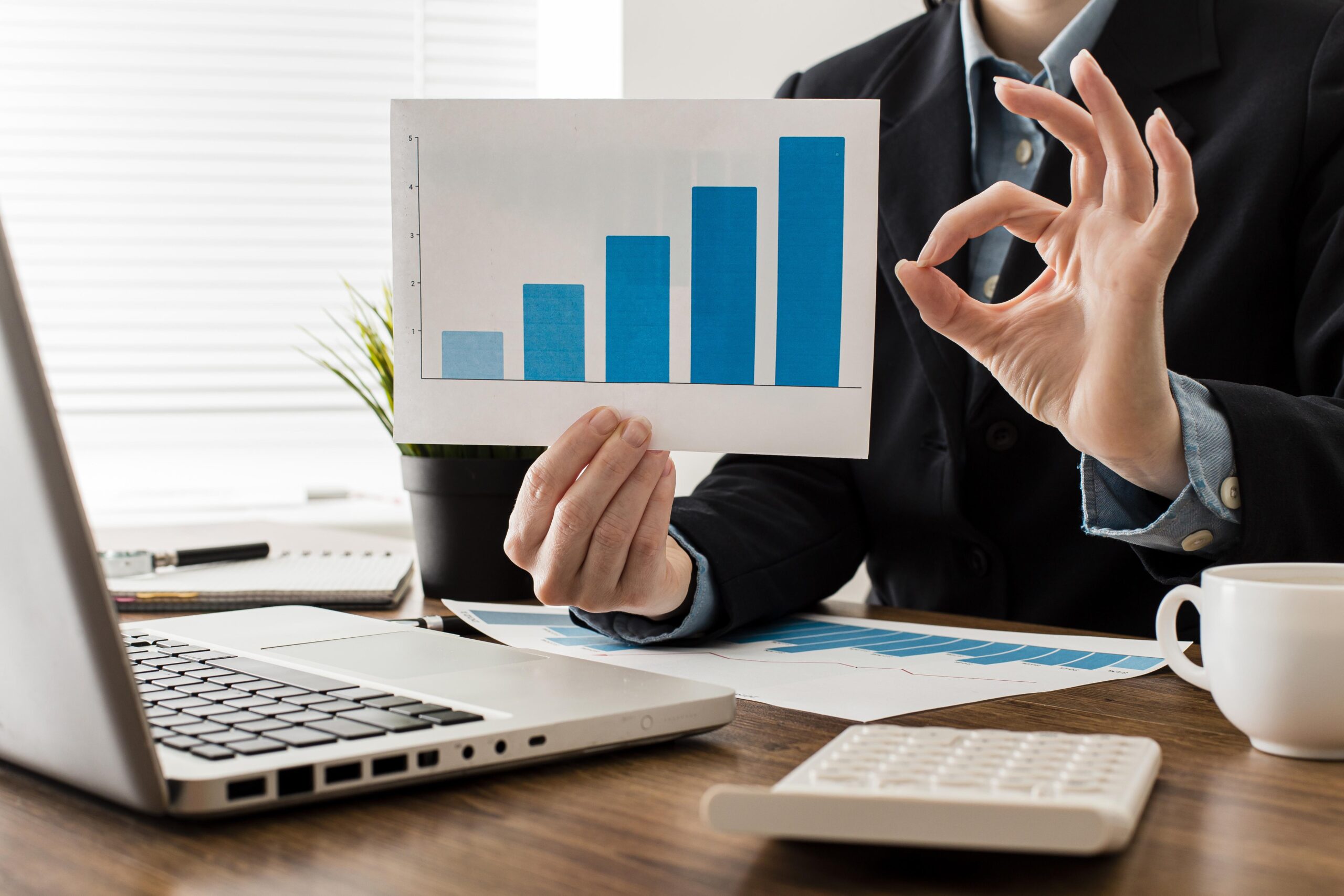 Businessman doing ok sign while holding growth chart
