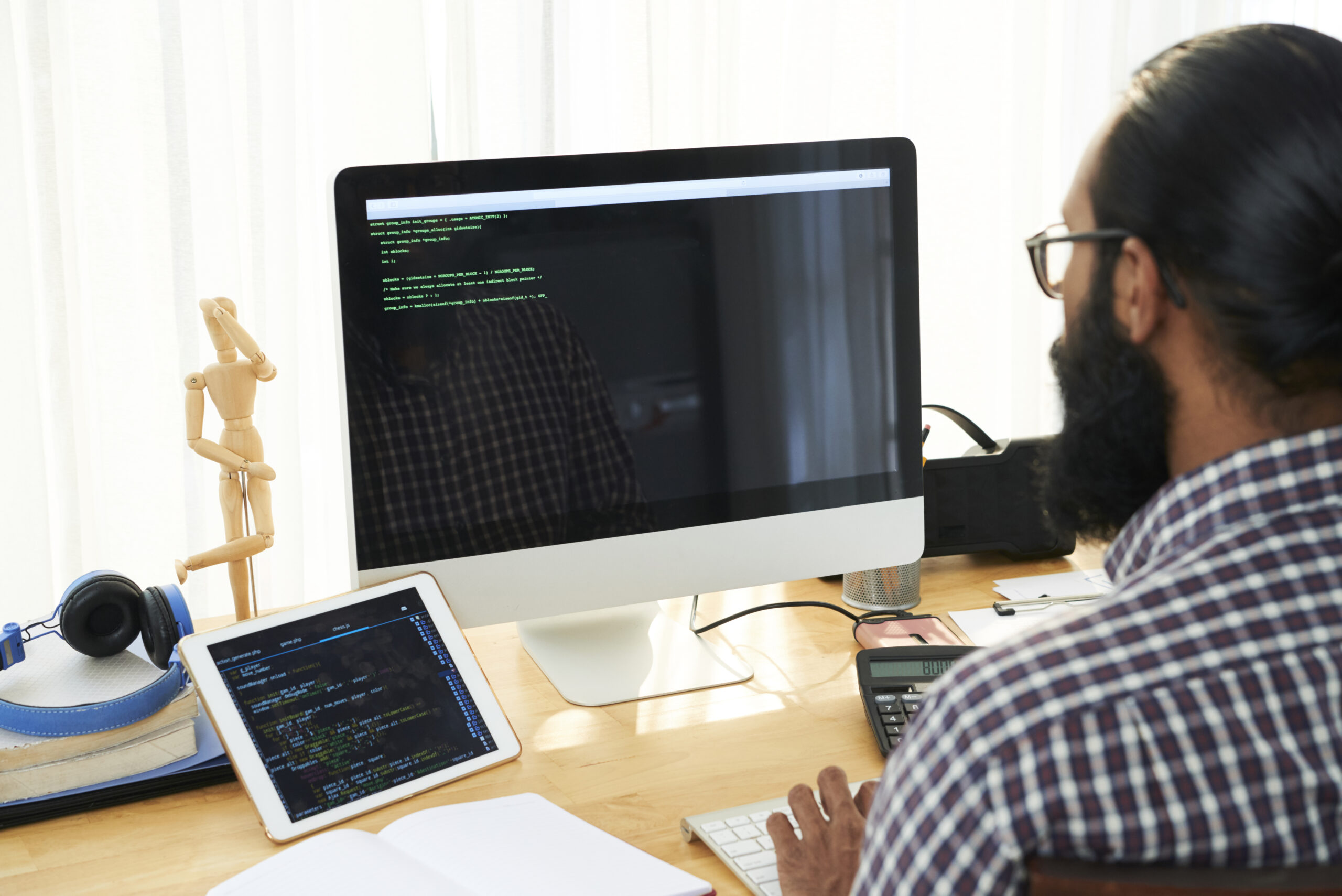 IT technician sitting by workplace in front of computer screen, analysing data or creating new code or language