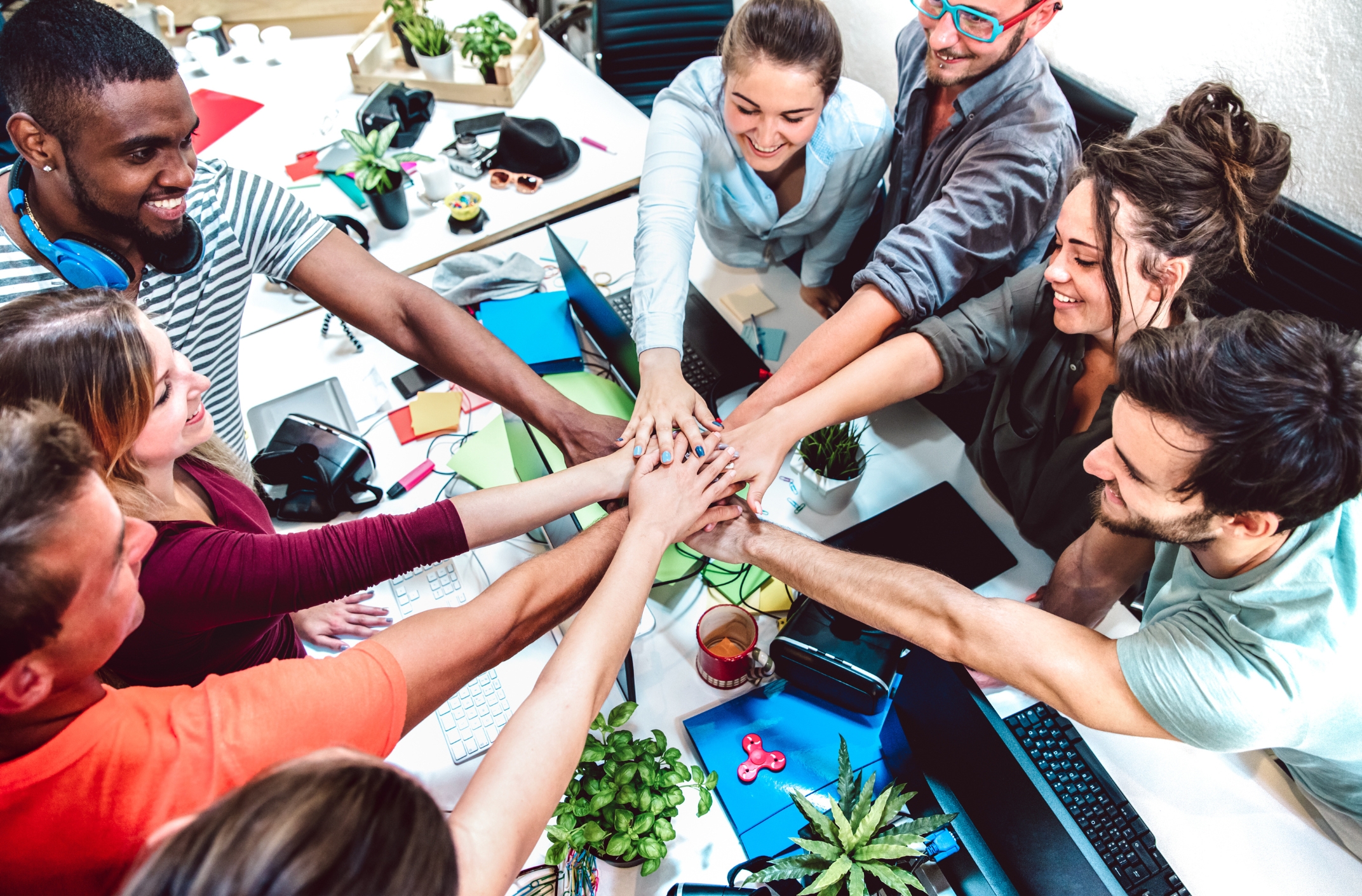 Young office workers placing hands on top of each other across the desk